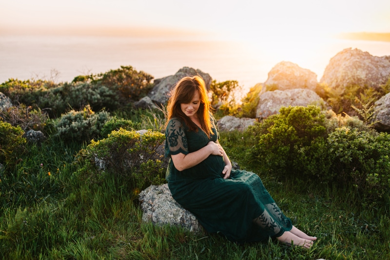 Maternity Photographer, woman sitting on a rock overlook the beach