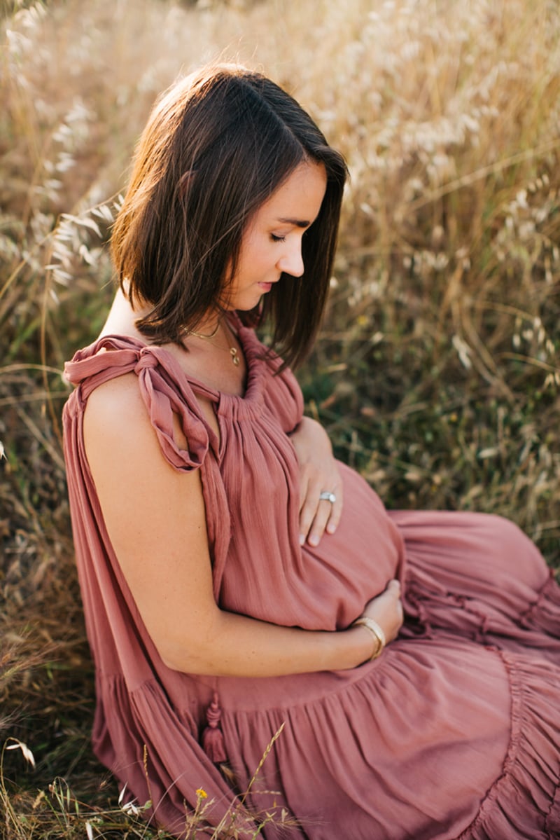 Maternity Photographer, woman kneeling down in a field