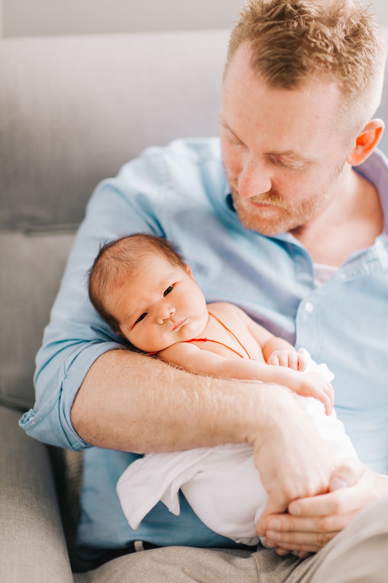 Newborn Photographer, father sitting on couch and holding baby