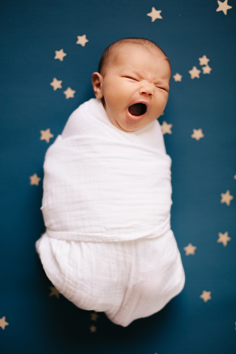Newborn Photographer, swaddled baby yawning on a star background