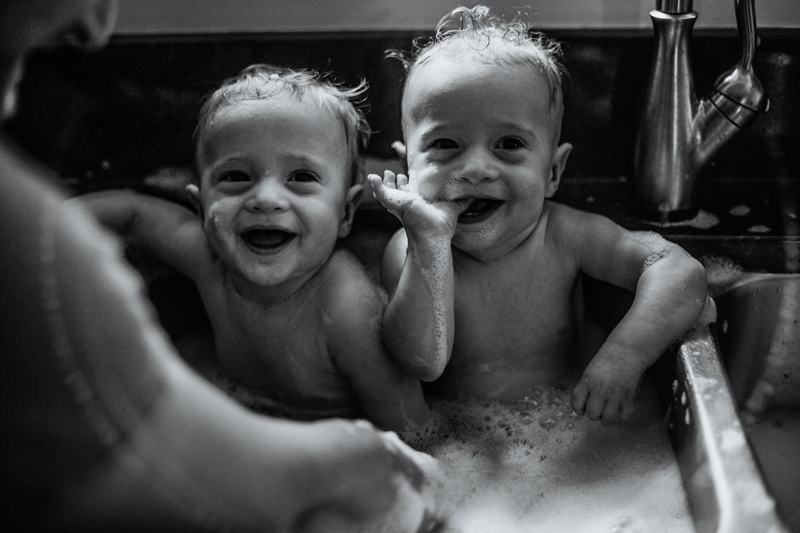 Family Photographer, black and white image of twins taking a bath in kitchen sink