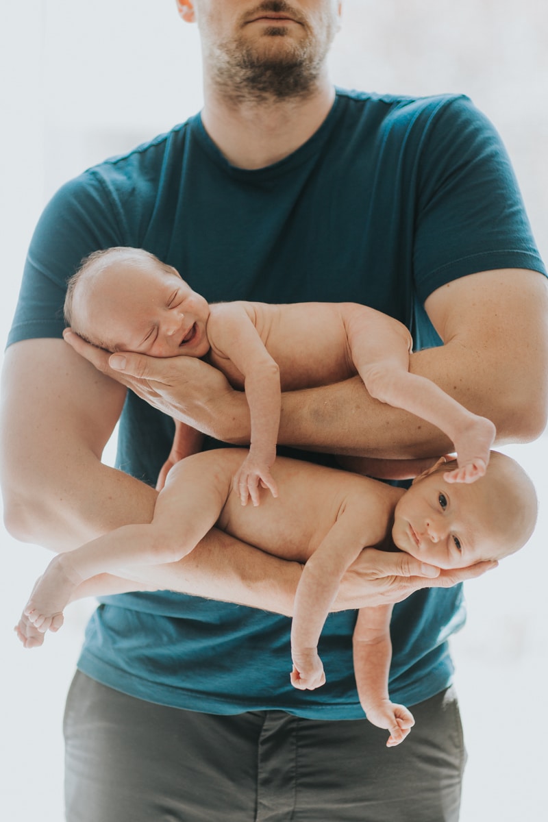 Newborn Photographer, father holding twins, one draped over each arm