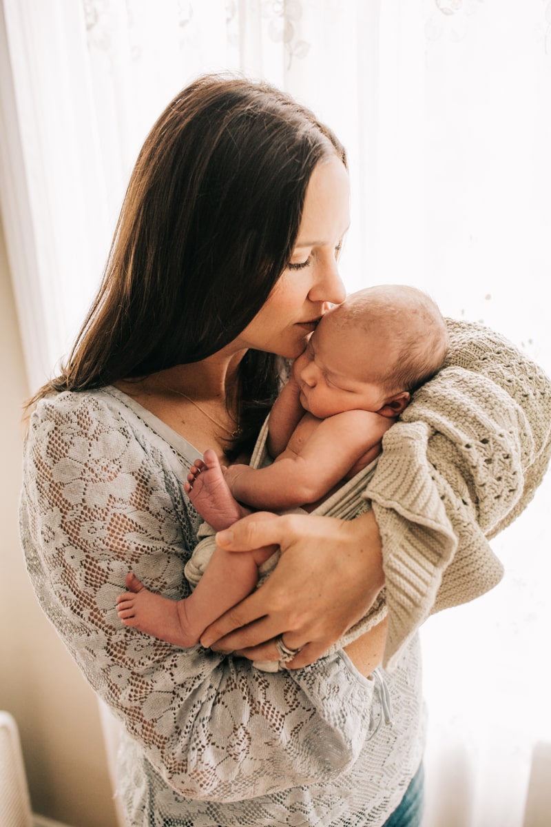 Newborn Photographer, mother kissing baby on the side of its head