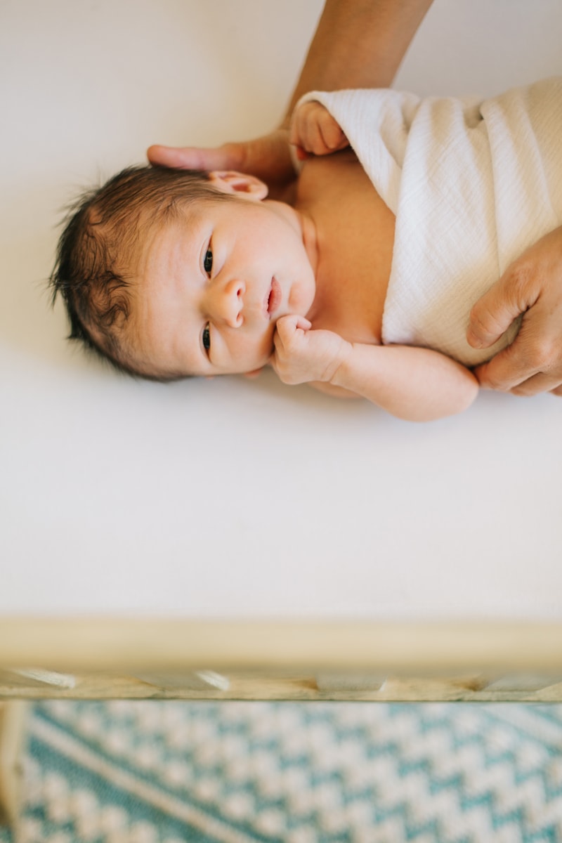 Newborn Photographer, baby laying on its side in parent's hands