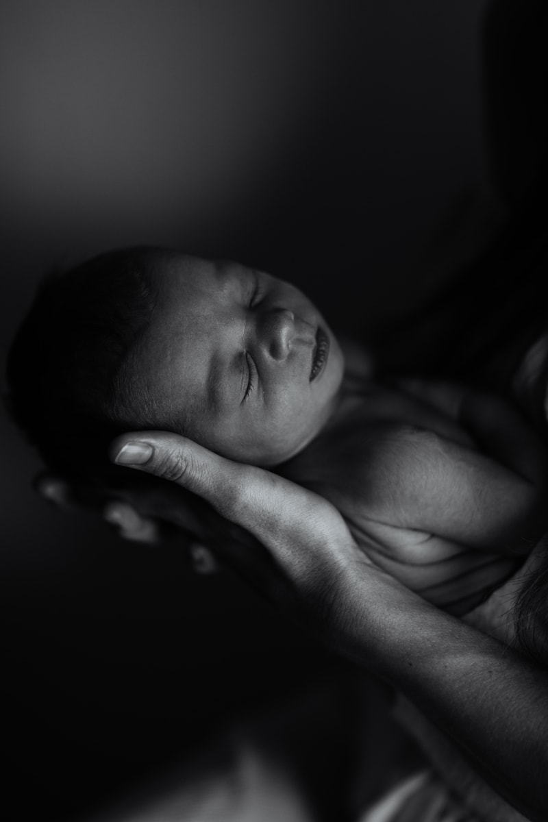 Newborn Photographer, black and white of baby sleeping in parent's arms